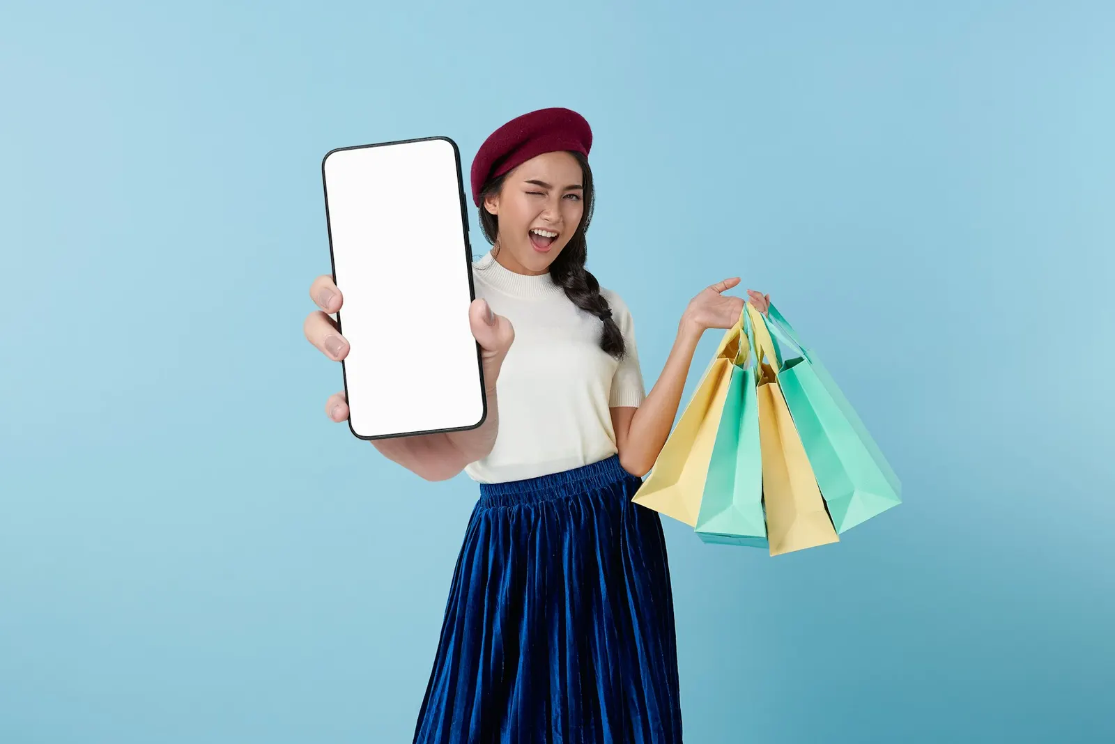 Una ragazza mostra lo smartphone con le borse della spesa in mano