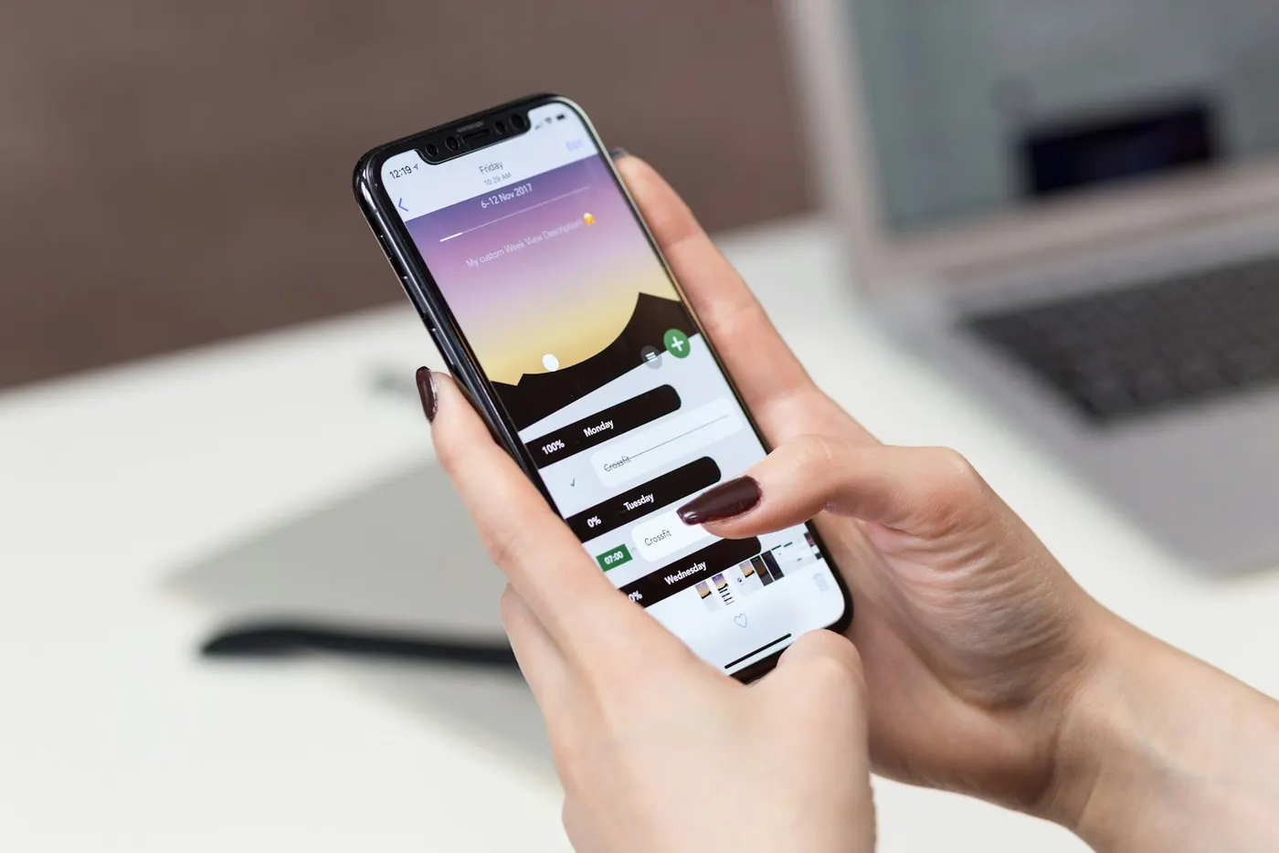 Mani che usano un'app sullo smartphone, con un portatile sullo sfondo